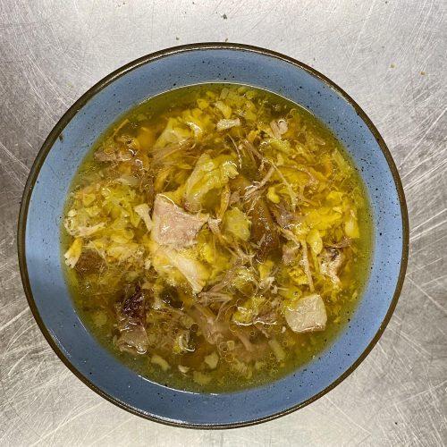 A hearty bowl of pork and cabbage soup with steam rising, garnished with fresh parsley