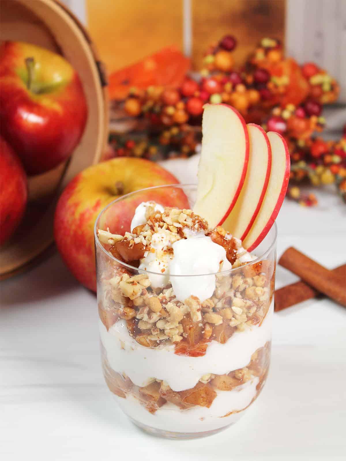 Apple crisp parfait with vanilla bean ice cream in a glass, garnished with apple slices