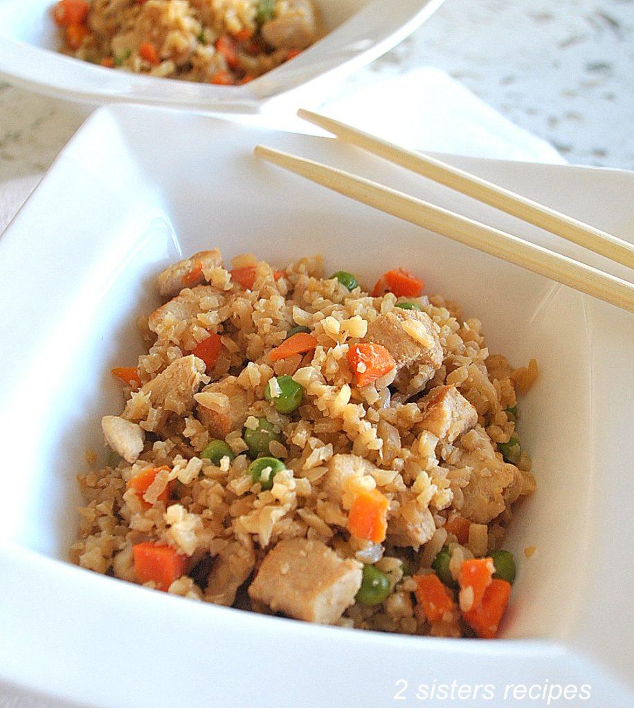 Ingredients for cauliflower rice chicken stir-fry laid out on a wooden countertop