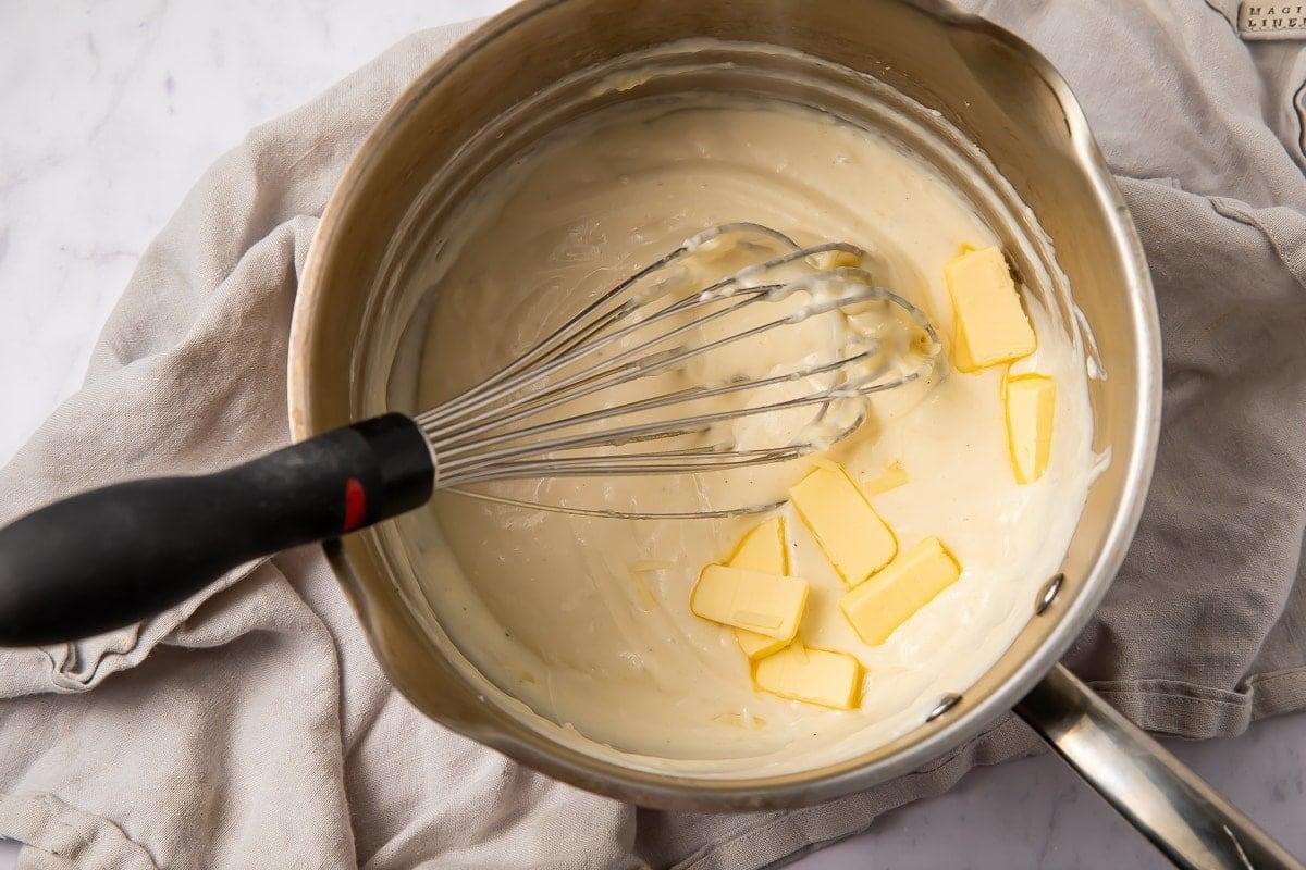Close up of the creamy Mornay sauce being poured over the Kötbullar