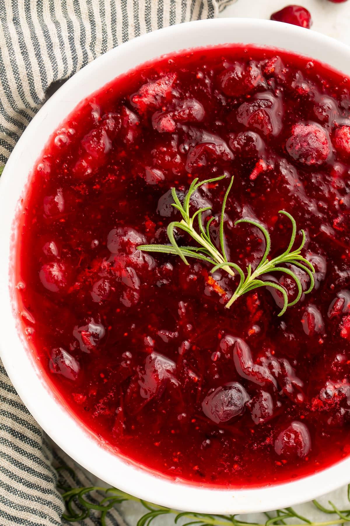 Close-up shot of a glossy, vibrant rosemary cranberry sauce with fresh rosemary sprigs