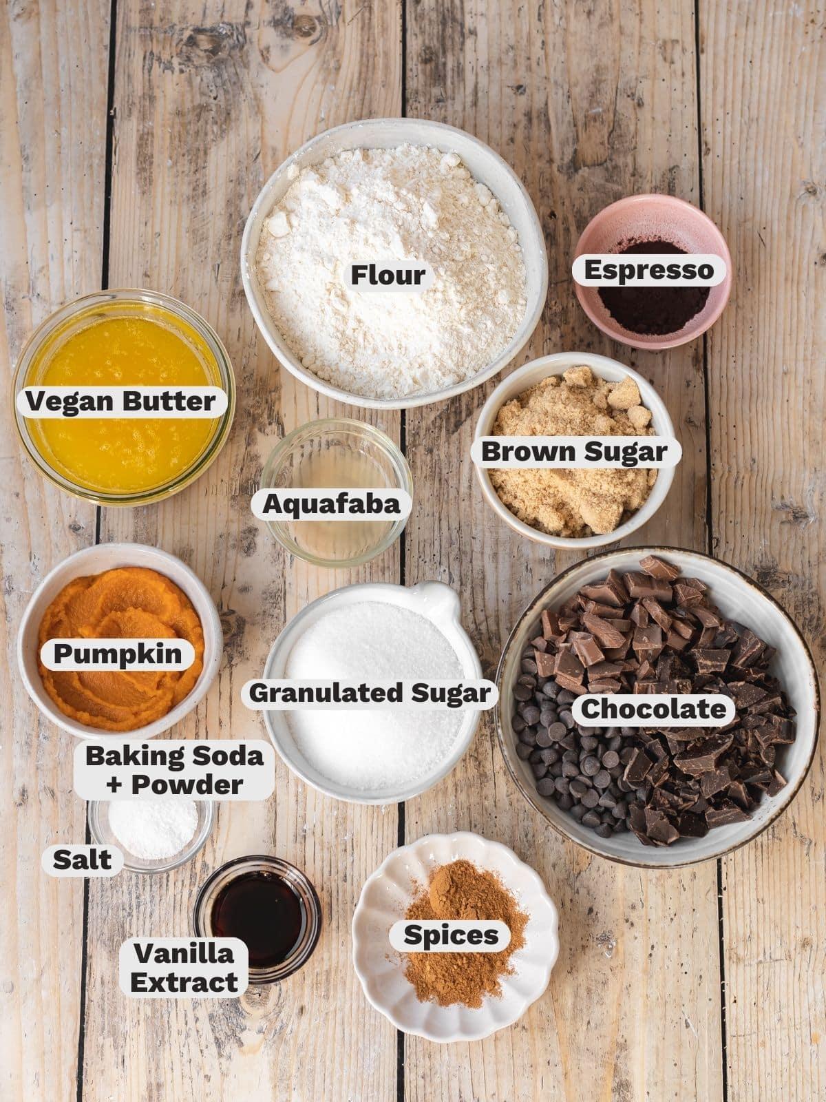Overhead shot of all the ingredients needed for pumpkin chocolate chip cookies laid out on a wooden surface