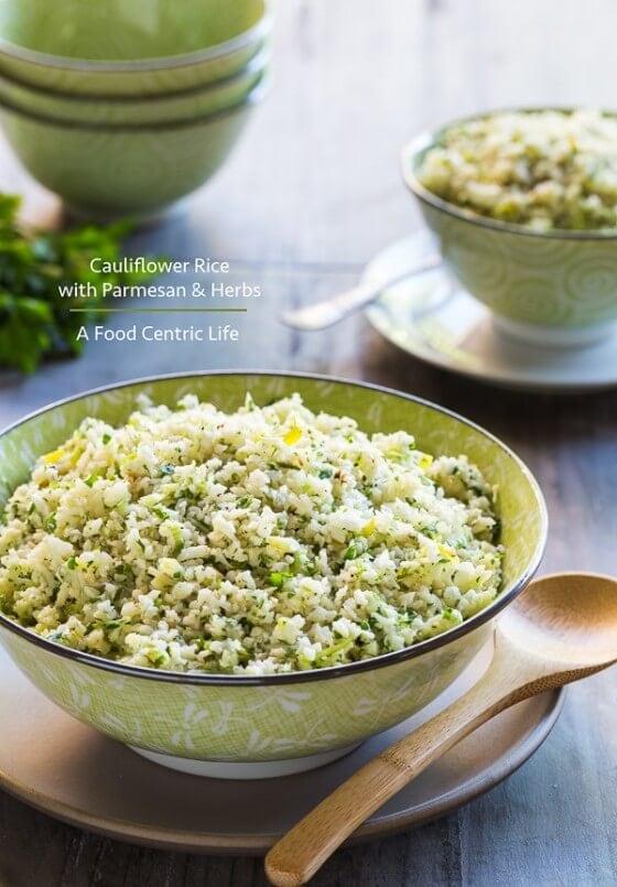 Close-up shot of a bowl of cauliflower rice with melted cheese, garnished with fresh herbs
