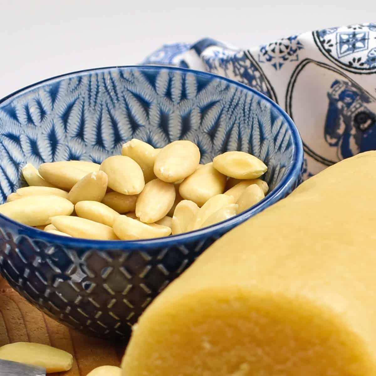 A rustic kitchen scene with a bowl of homemade almond paste and fresh almonds