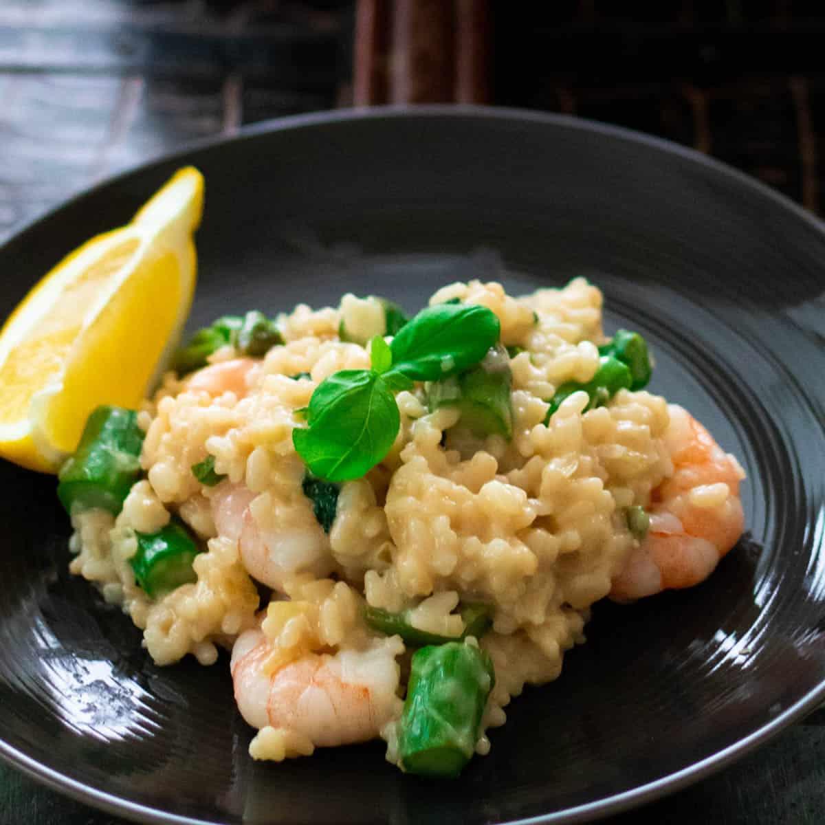 Close-up shot of a creamy asparagus risotto with grilled shrimp and a lemon wedge on top