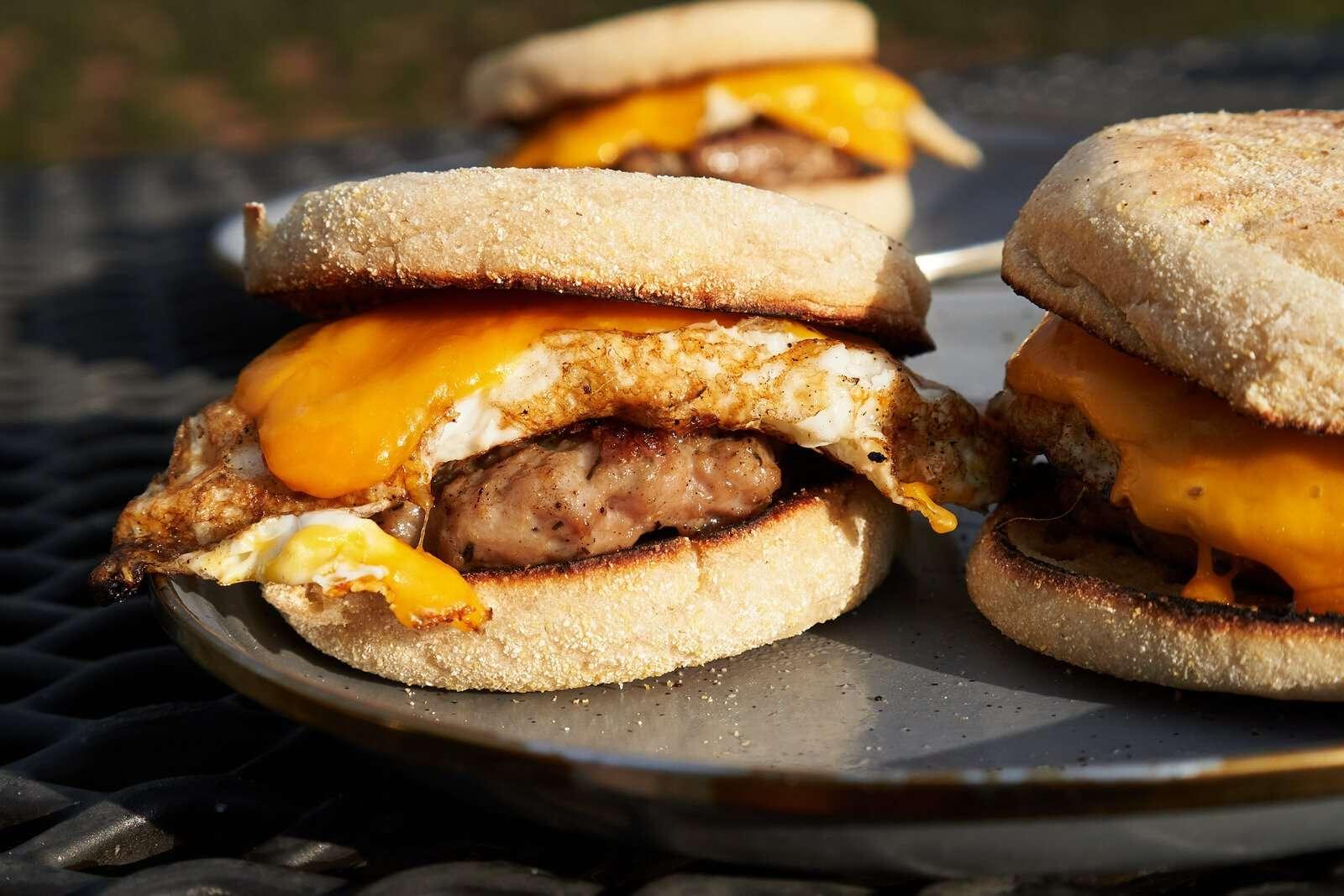 A delicious sausage, egg, and cheese sandwich on a picnic blanket outdoors