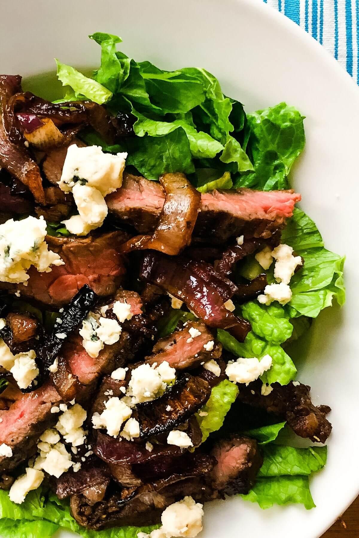 Close-up of a steak salad with blue cheese and caramelized onions
