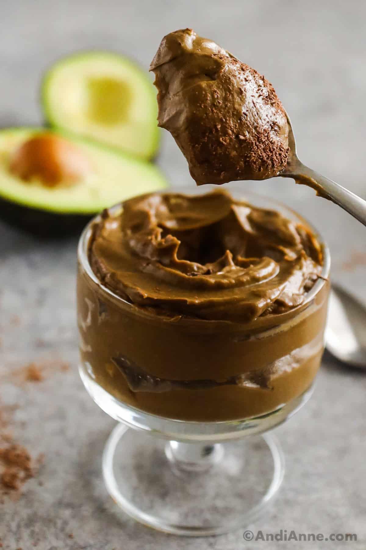 A hand scooping Hemp Seed Avocado Chocolate Mousse from a glass bowl