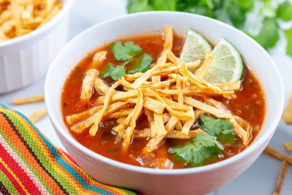 Close up shot of a bowl of Spicy Vegan Tortilla Soup with various toppings