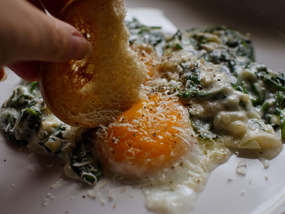 Close-up shot of golden brown Florentine Eggs in a skillet, showing creamy yolks and wilted spinach