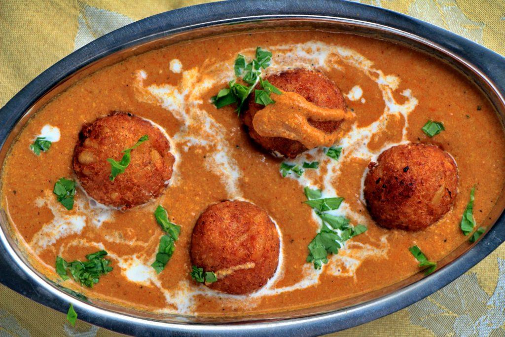 A close-up shot of a single Malai Kofta, glistening with sauce.
