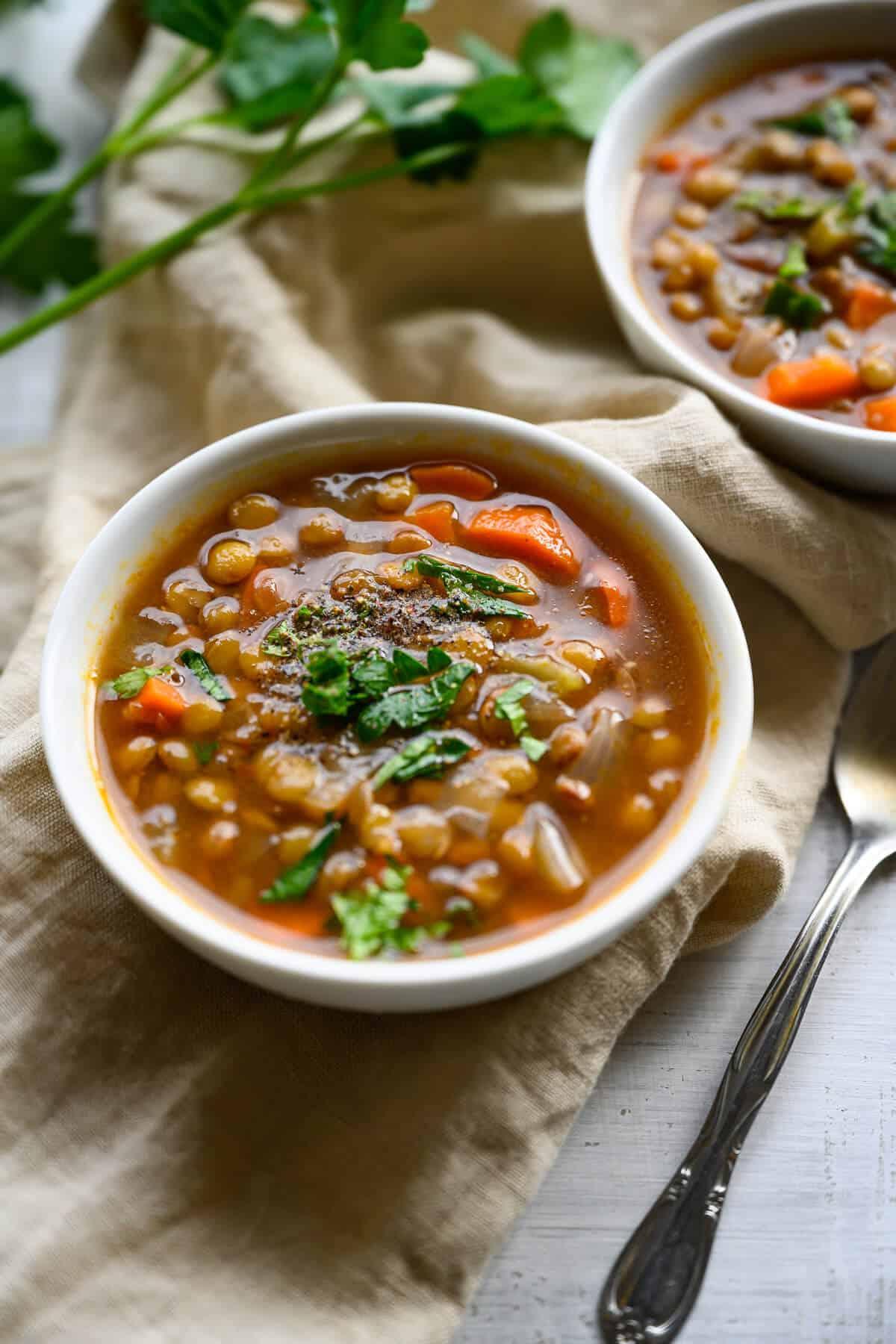 Close-up shot of a steaming bowl of lentil soup with vegetables.