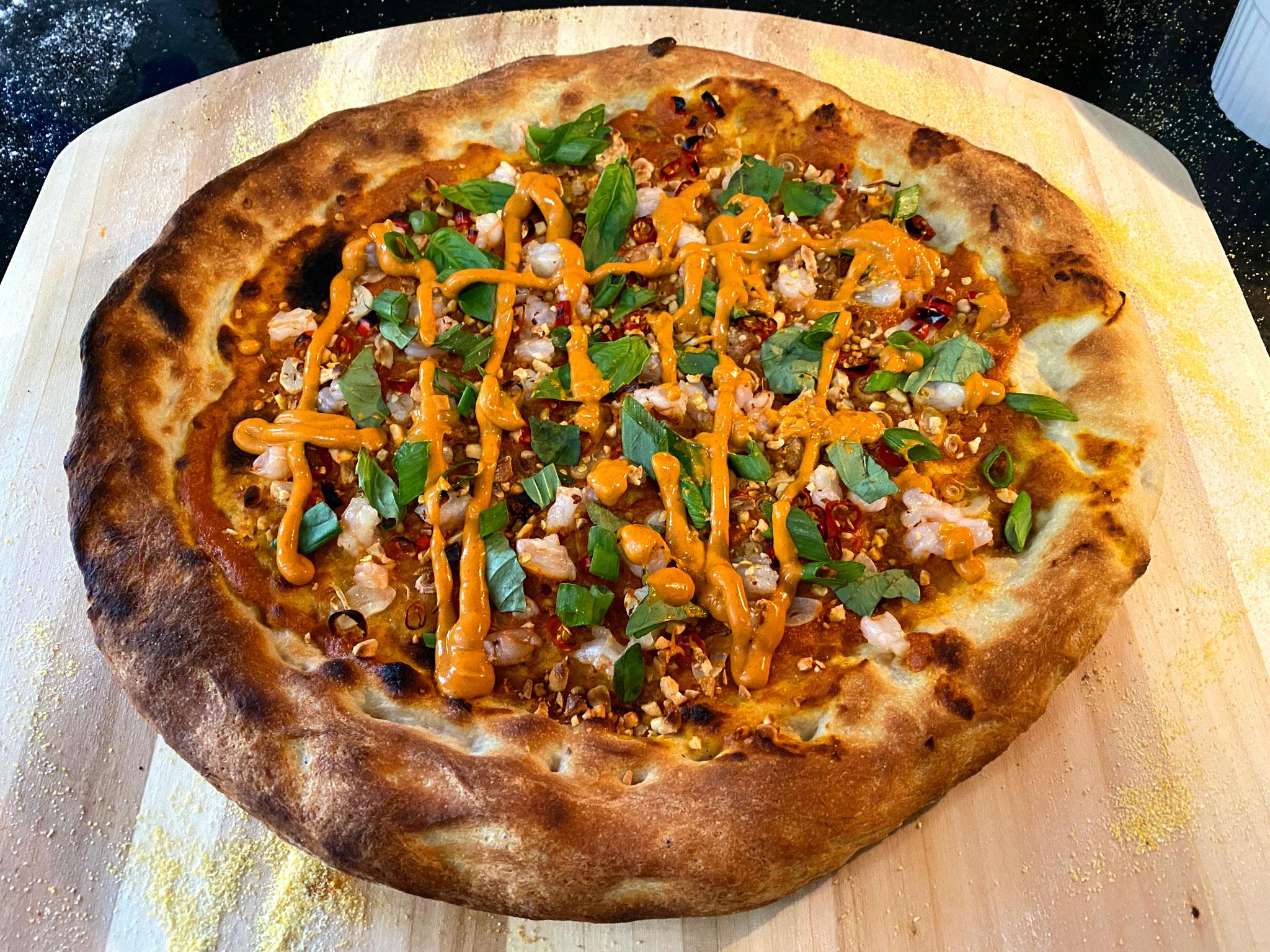 Kerala prawn curry pizza with vibrant toppings on a wooden table
