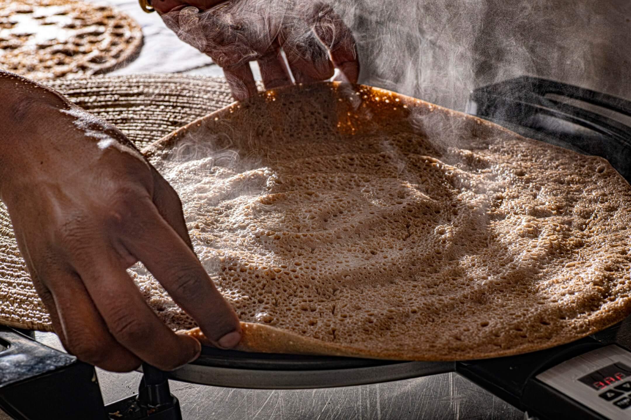 Hands preparing injera batter