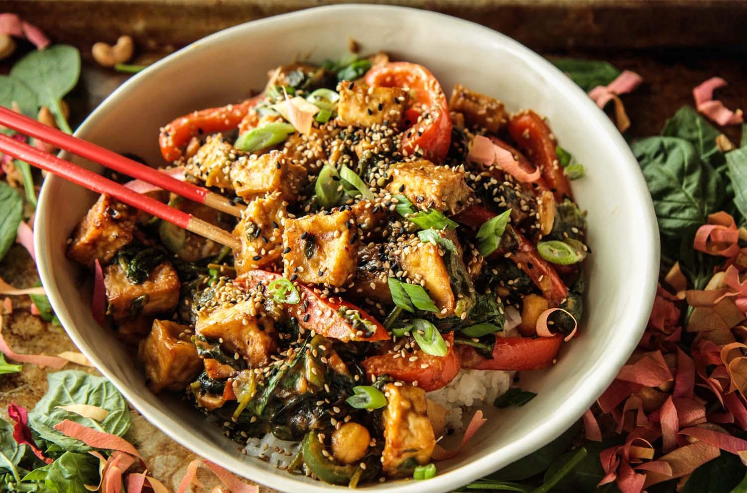 overhead shot of a colorful garlic ginger tofu and cabbage stir-fry with various toppings