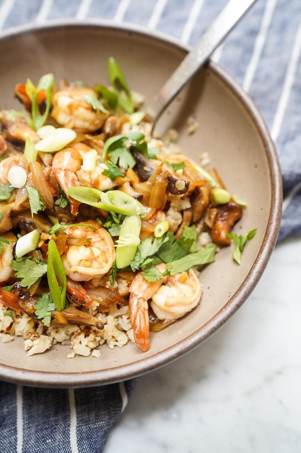 Close up shot of a bowl of cauliflower rice with shrimp stir-fry