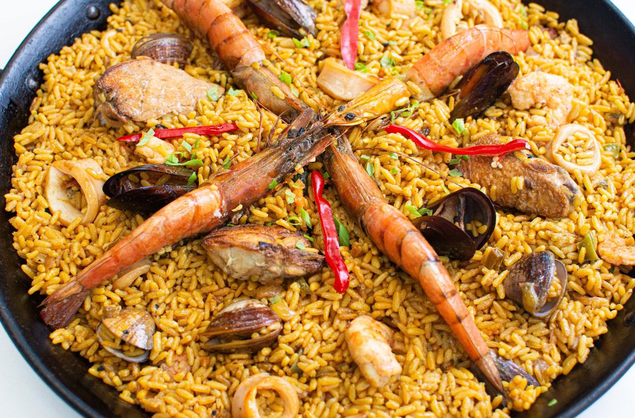 A beautifully plated paella dish, showcasing the vibrant colors of the rice, duck, and blackberry reduction