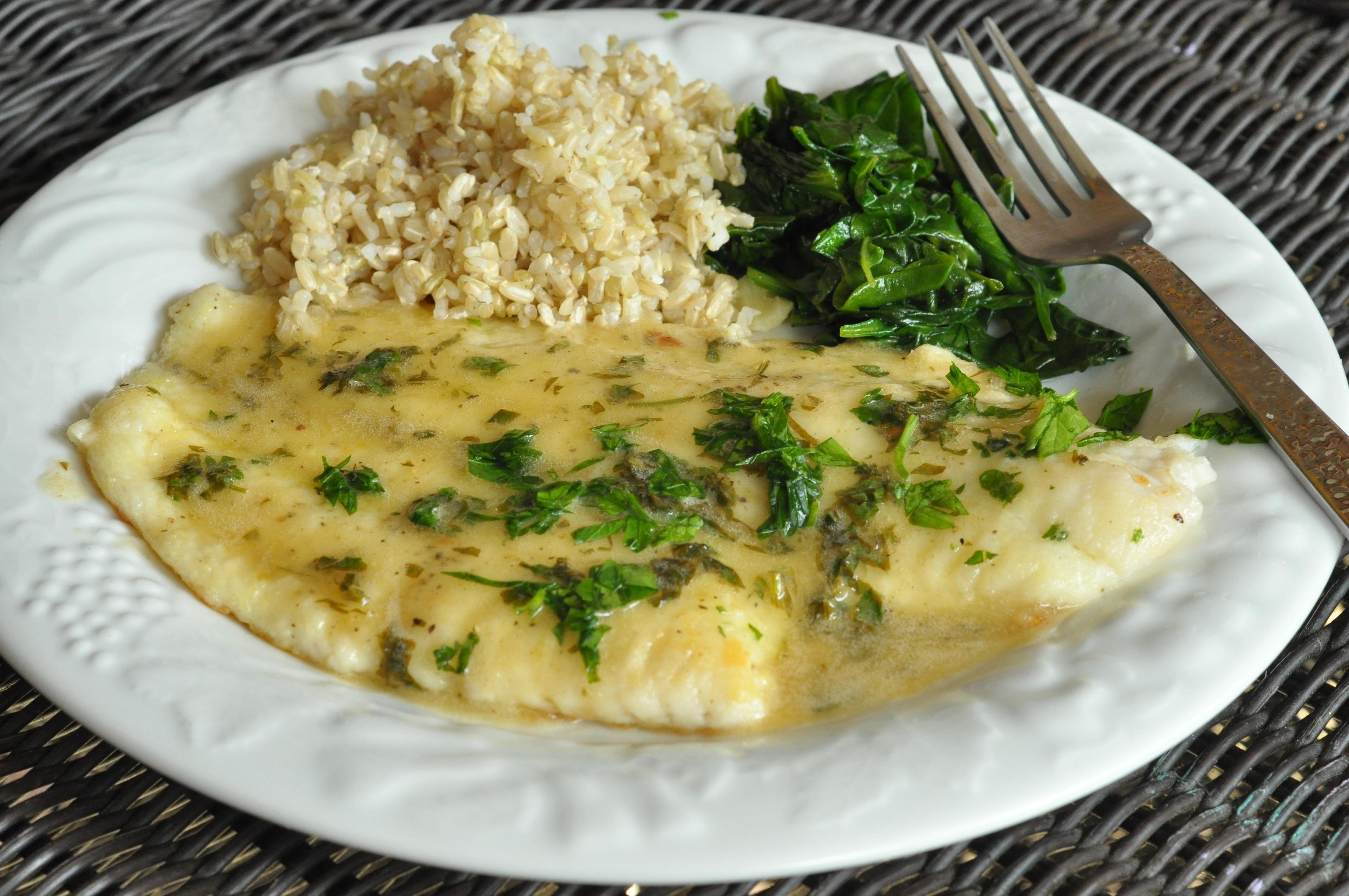 person pouring parsley butter sauce over steamed lemon sole