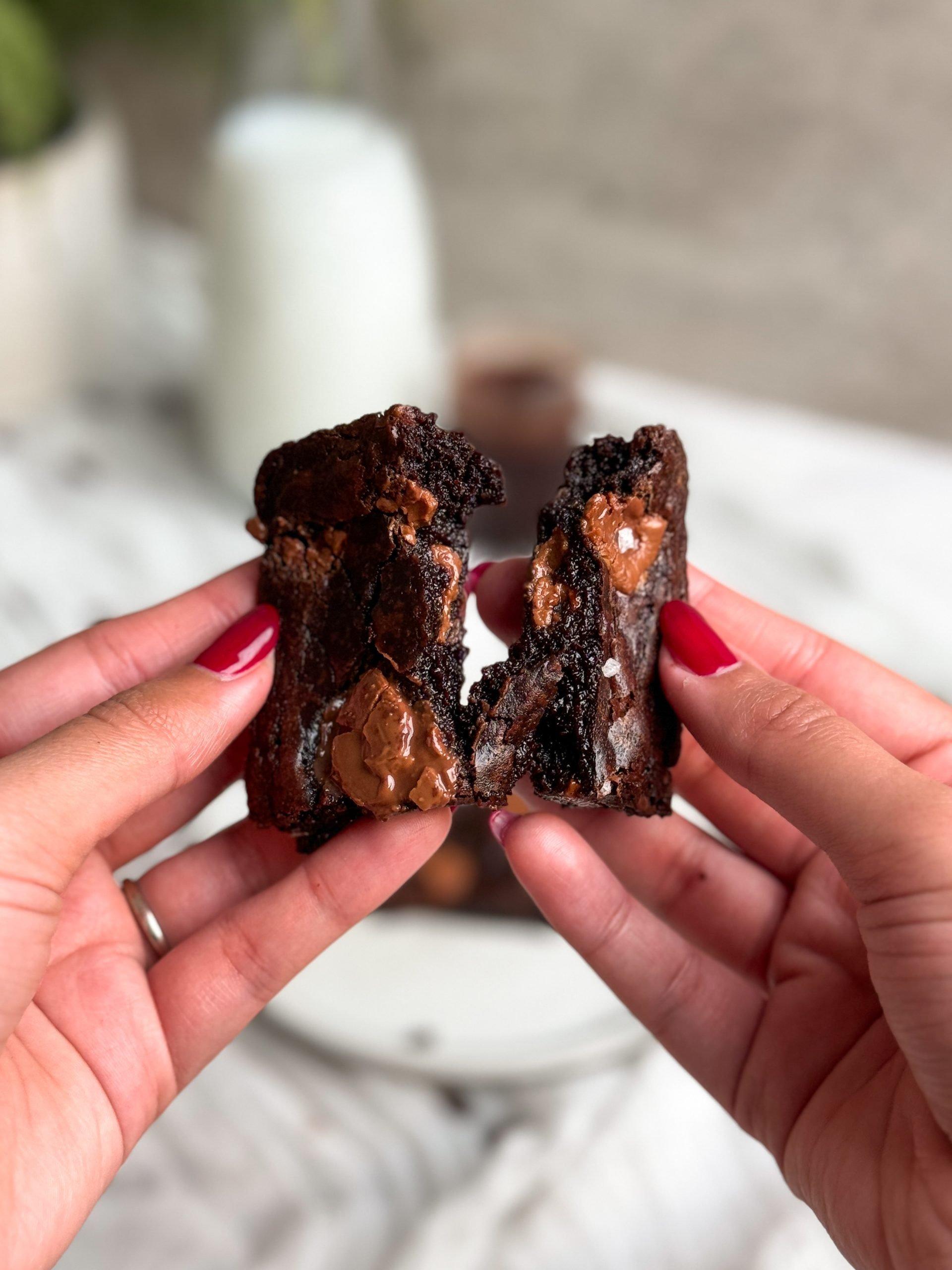 A hand holding a cut brownie, showing its fudgy texture