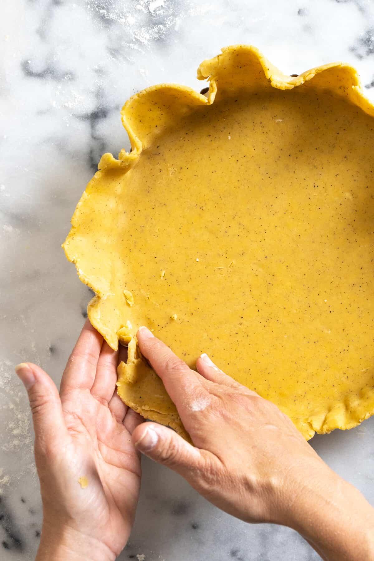 Close-up shot of a person's hands carefully filling a tart shell with lingonberry filling.