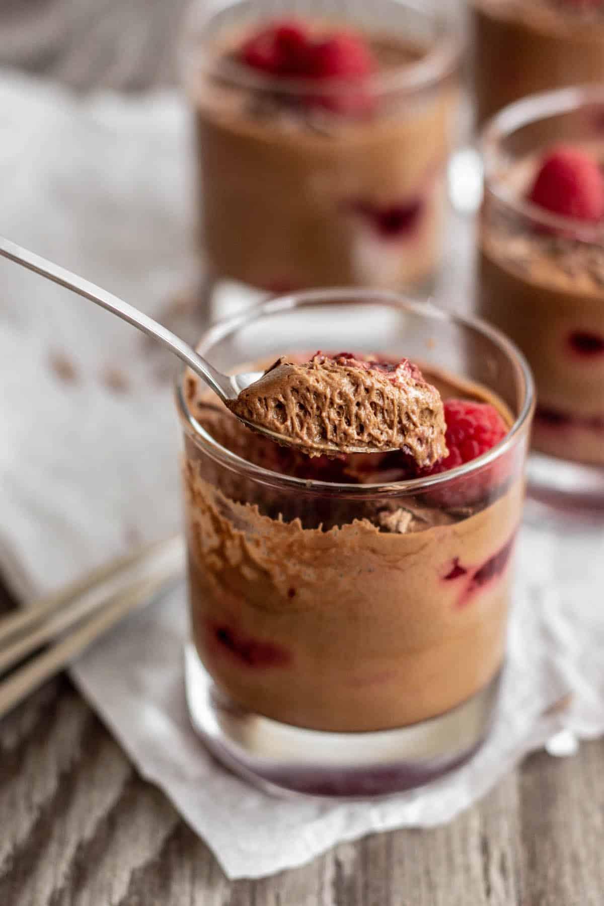 Close-up of a spoonful of chocolate mousse, showing its creamy texture, with a raspberry on top