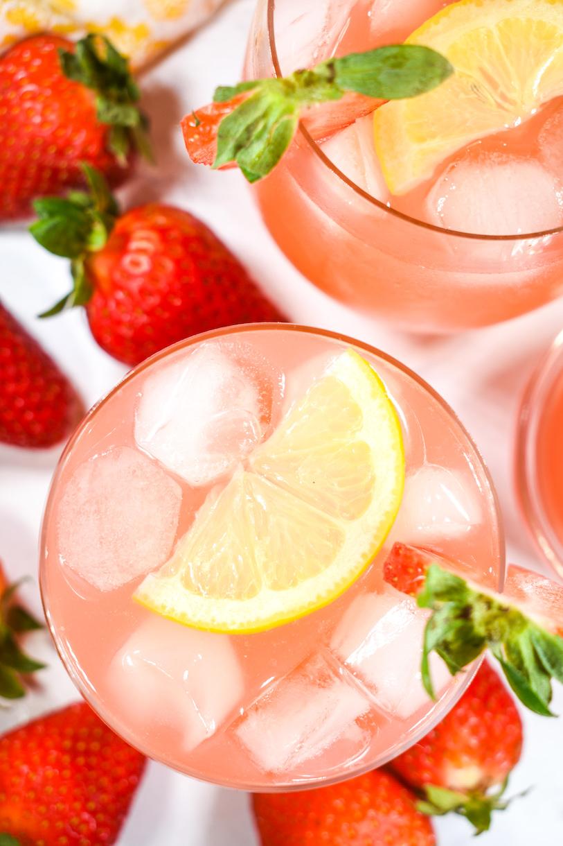 Refreshing glass of homemade strawberry rhubarb lemonade with fresh fruit and ice