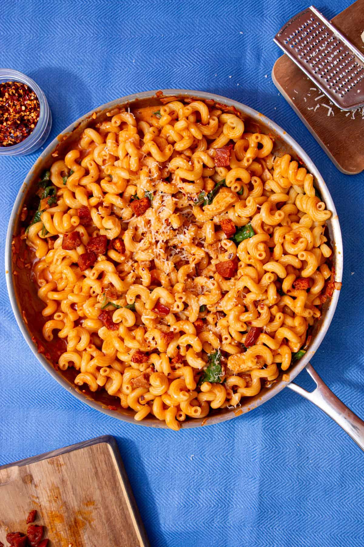 overhead shot of chicken and chorizo pasta being stirred in a skillet