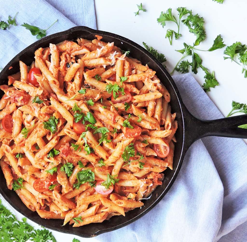 creamy pasta sauce simmering in a skillet, with pasta being added
