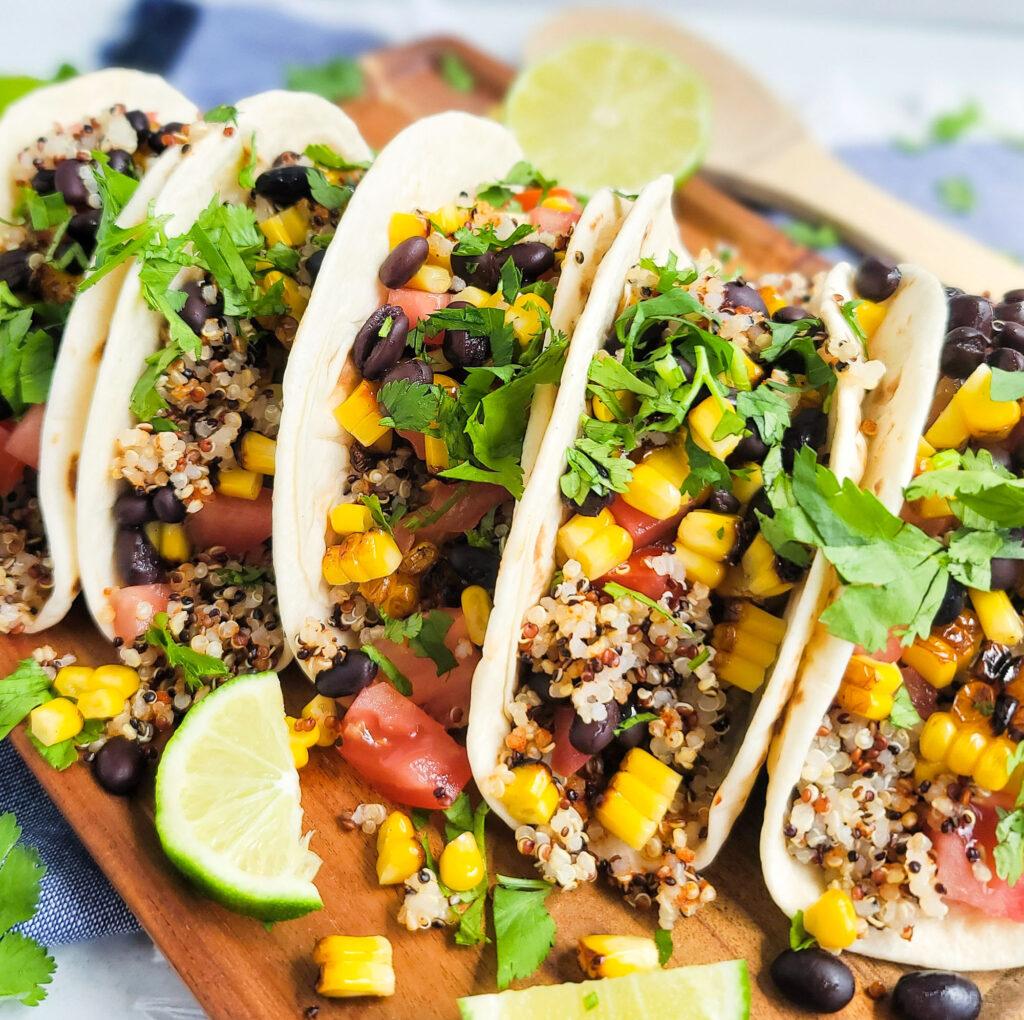 Close-up shot of grilled corn and black bean tacos on a rustic wooden table