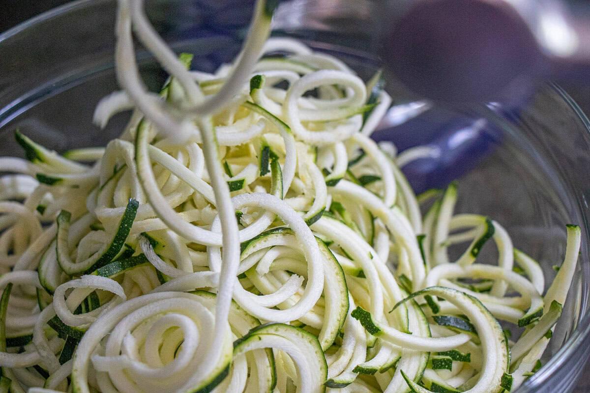 Close-up of Spicy Peanut Zoodles being tossed in a bowl