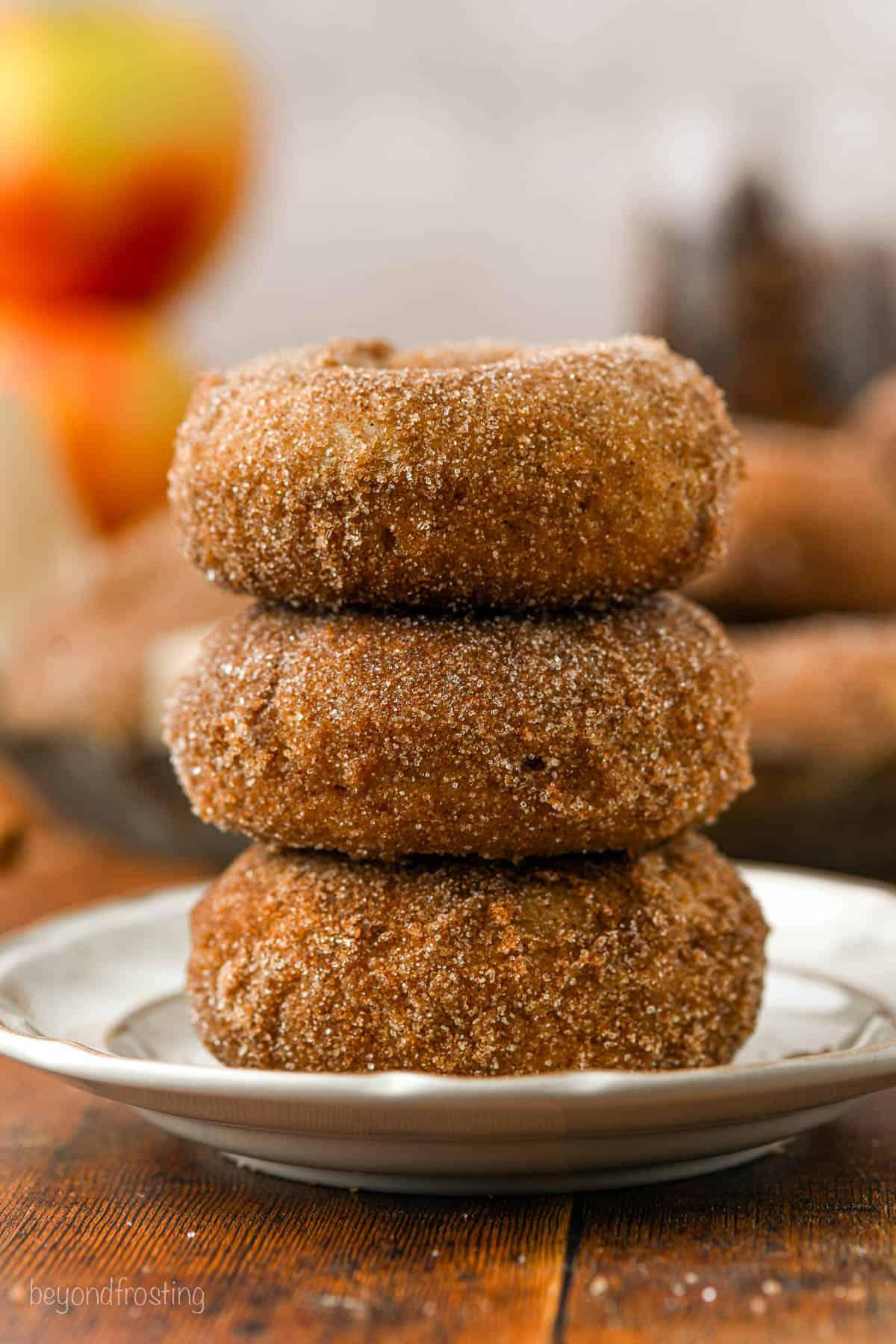 A plate of golden brown apple cider donuts with a generous drizzle of maple glaze