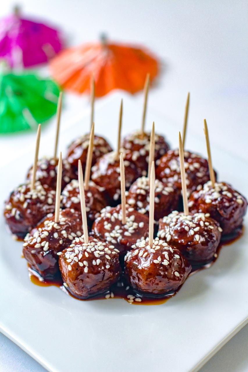 A group of friends enjoying a meal together, with a bowl of spicy Szechuan plant-based meatballs in the foreground