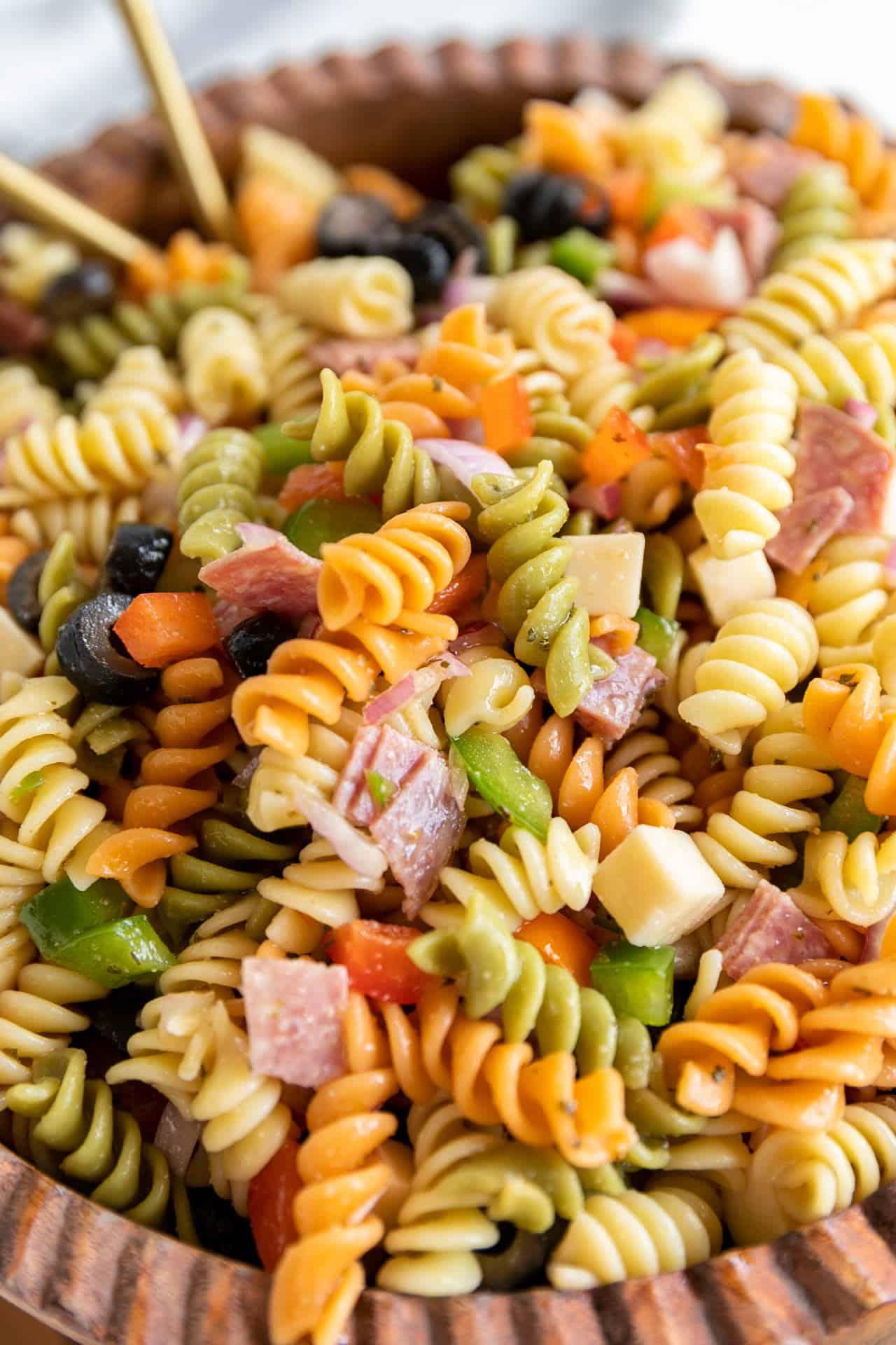 close-up shot of a person assembling the pasta salad in a large bowl