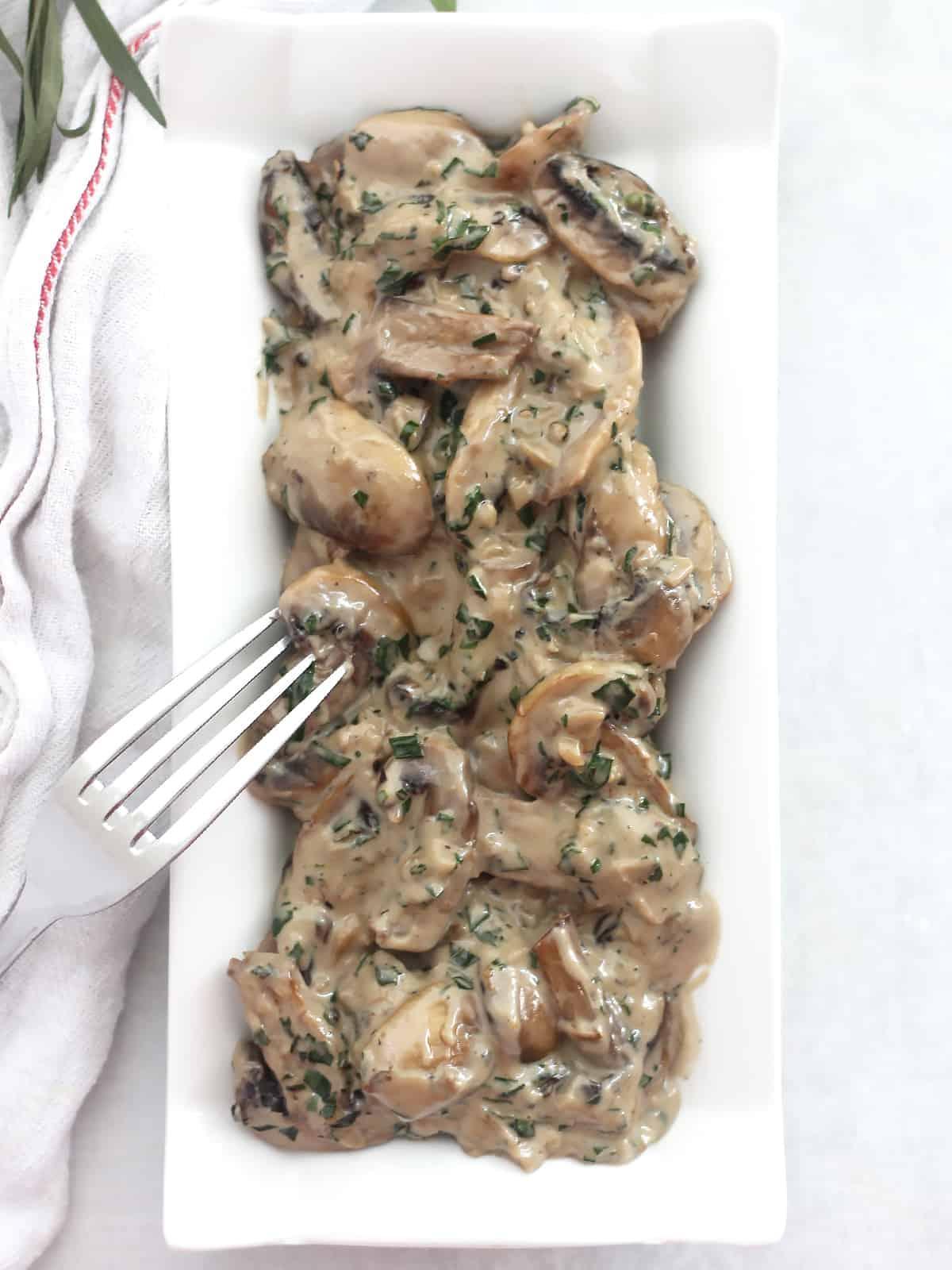 A plate of sautéed mushrooms with cream and tarragon garnished with fresh herbs