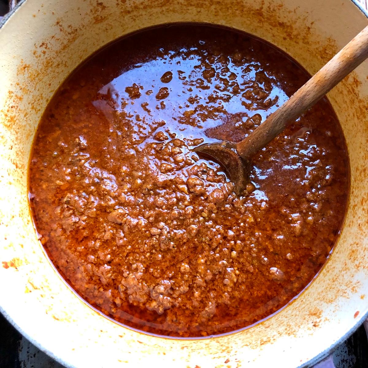 Close-up shot of a simmering bolognese sauce in a rustic saucepan