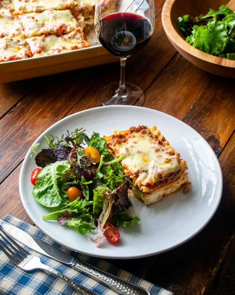 A table setting with a slice of zucchini lasagna and a side salad.