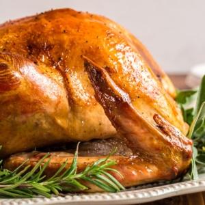 Close up shot of a beautifully roasted turkey with crispy skin and herbs