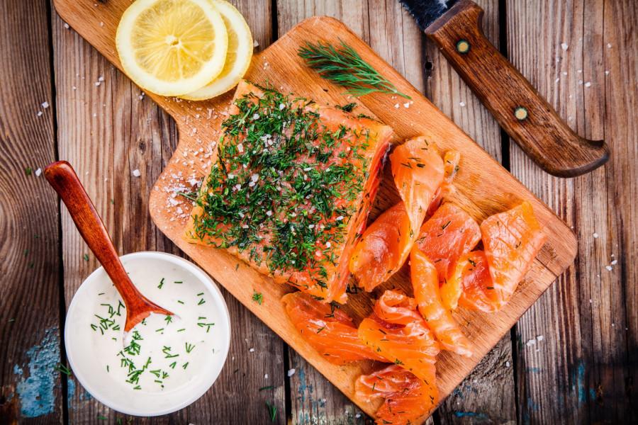 slices of gravlax arranged on a wooden board, garnished with fresh dill