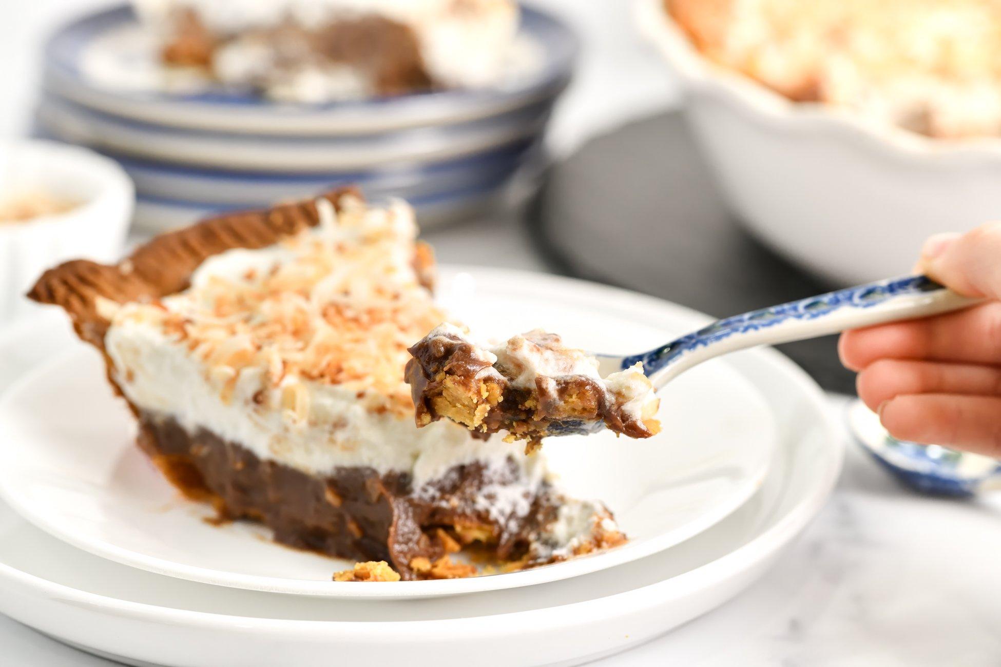 A close-up shot of a slice of coconut cream pie with warm chocolate fondue drizzled over it
