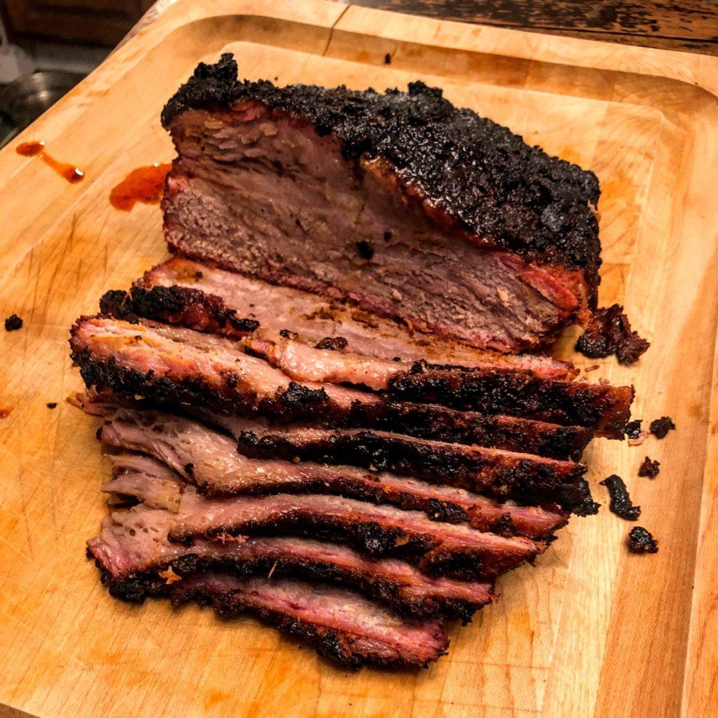 Close-up shot of a perfectly smoked brisket with a glistening mustard glaze