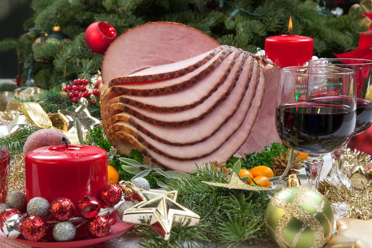 A beautifully carved Christmas ham on a platter with side dishes
