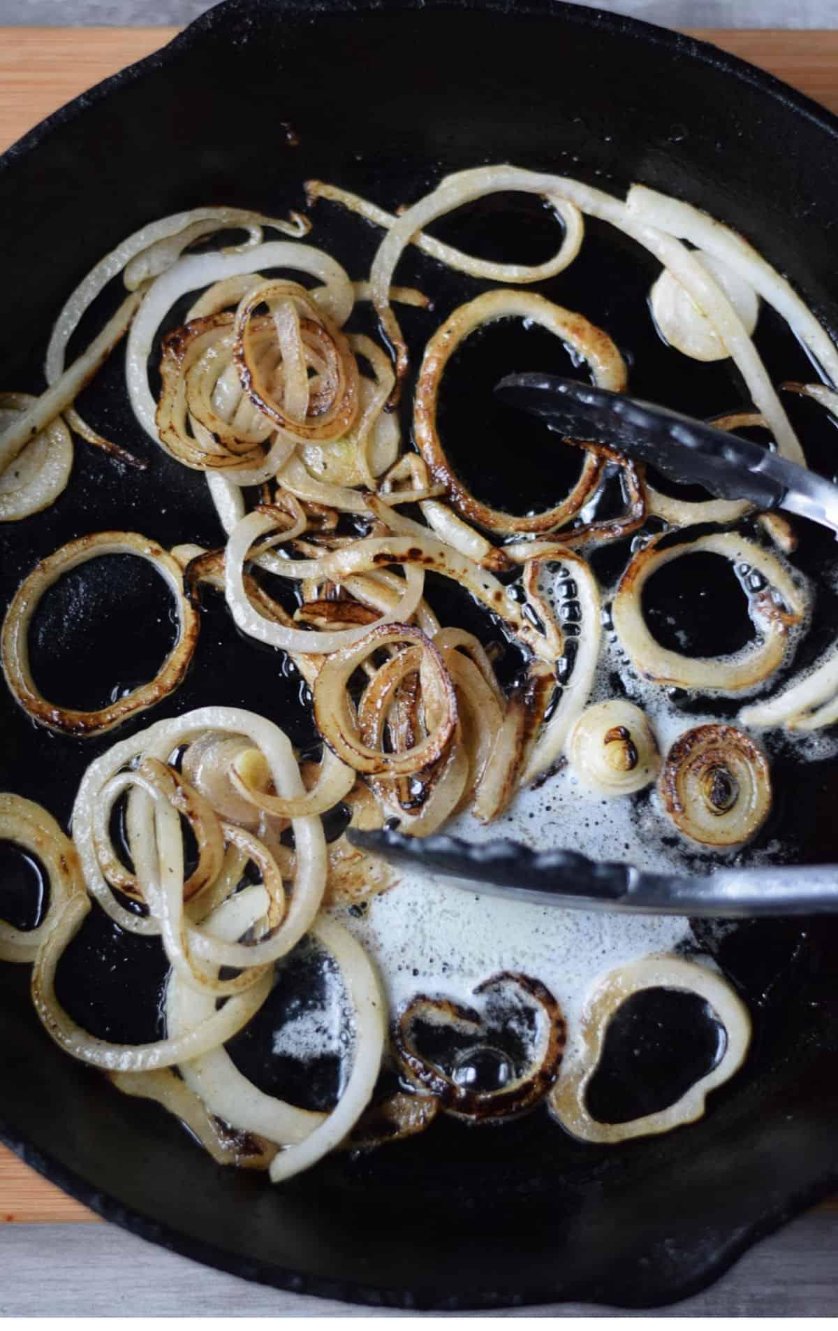 Image showing the process of making the burger: burger patties sizzling in a pan, caramelized onions cooking in a skillet, assembled burger.