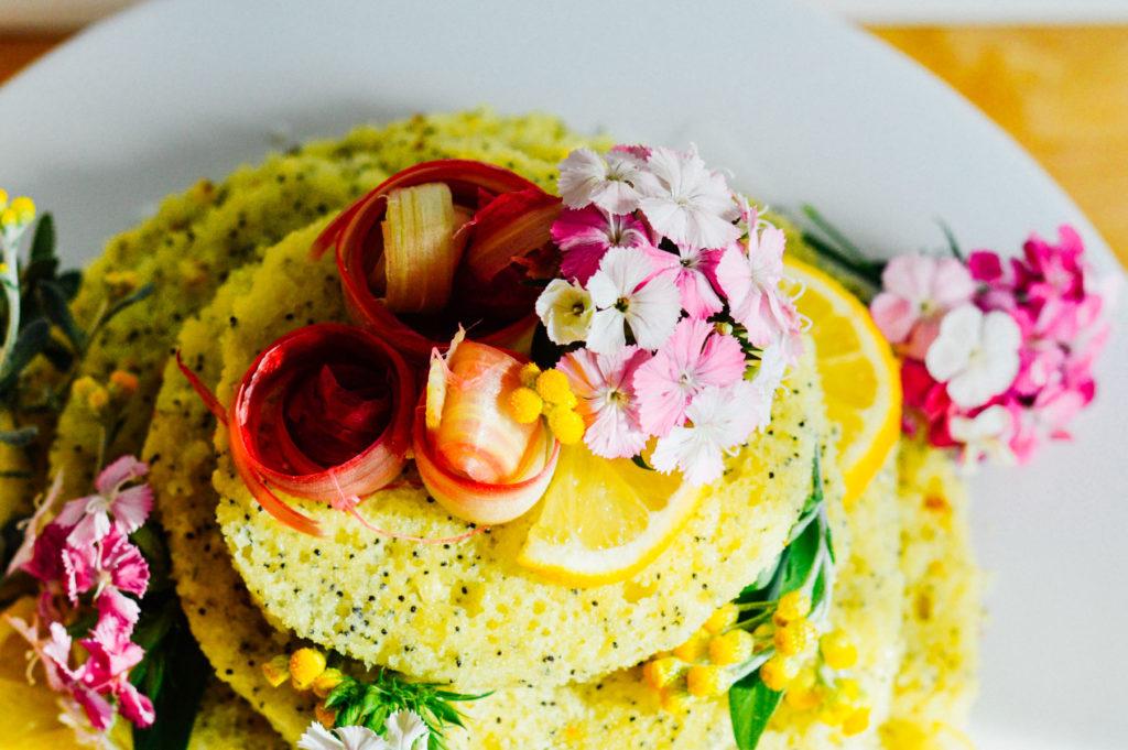 Overhead shot of a lemon poppy seed cake surrounded by spring flowers