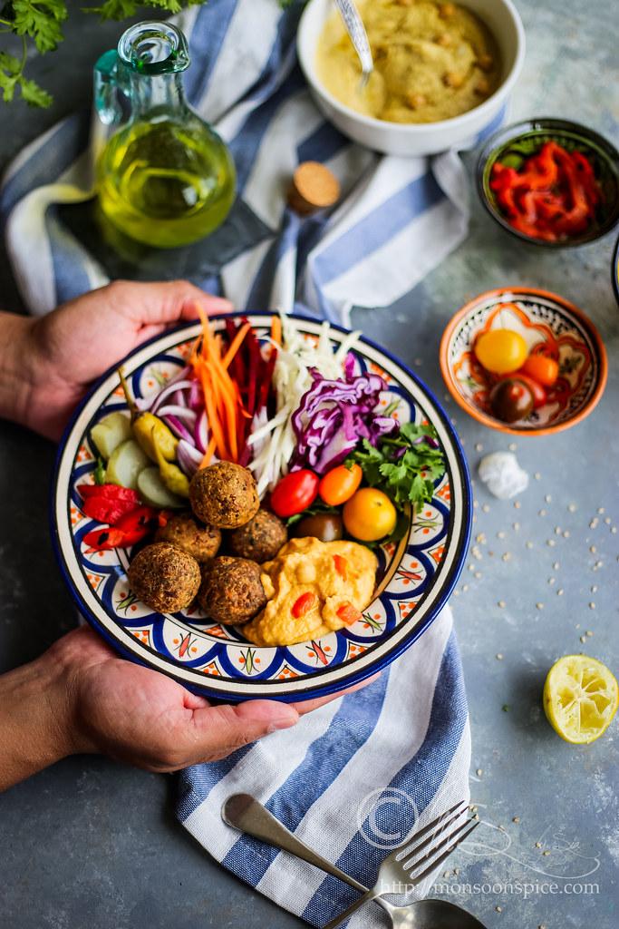Close-up shot of golden-brown falafel with vibrant turmeric hue, served in a pita with hummus and tahini drizzle