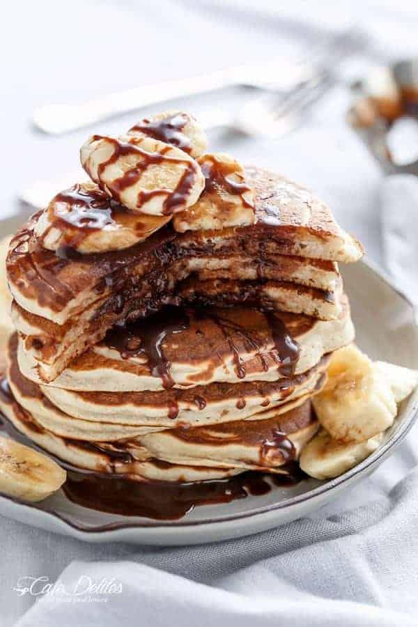 Stack of fluffy banana pancakes drizzled with Nutella, garnished with fresh banana slices