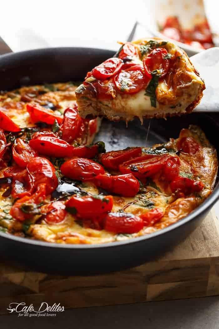 A rustic kitchen setting with a Caprese Frittata on the table, surrounded by fresh ingredients