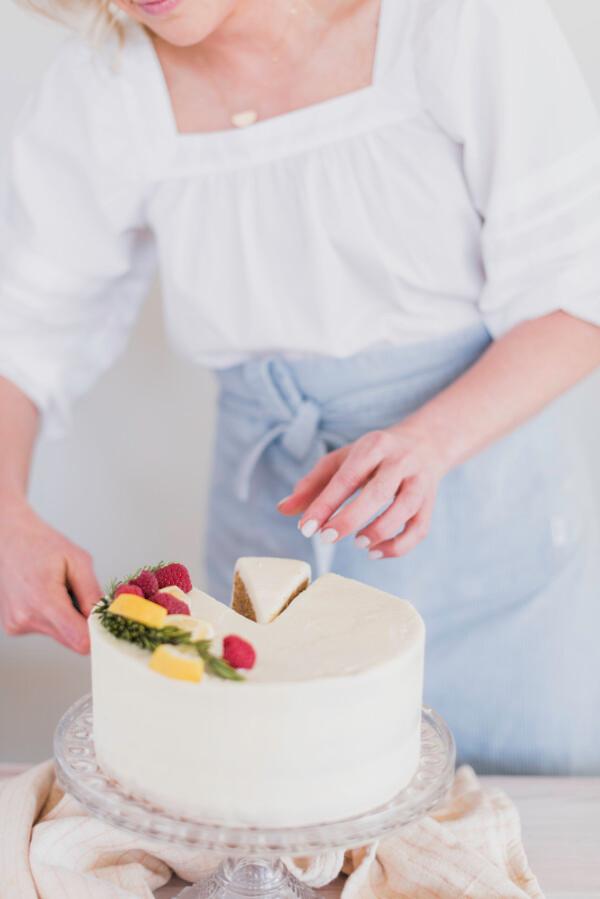 Person carefully frosting a lemon and gingerbread cake