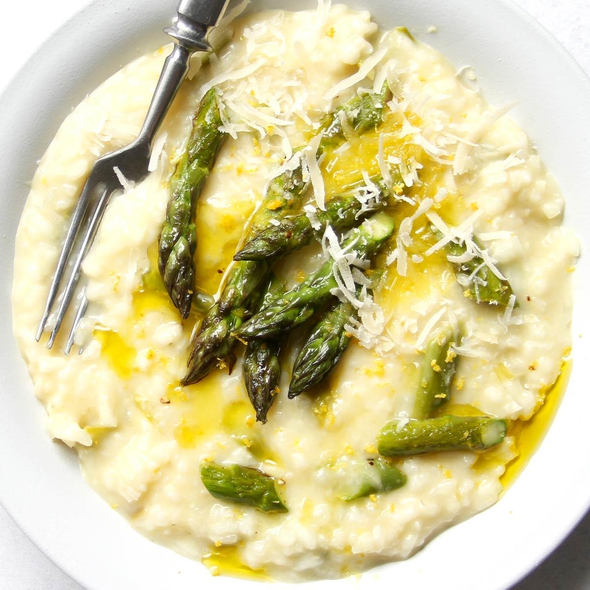 A creamy asparagus risotto with feta cheese sprinkled on top, garnished with fresh asparagus spears