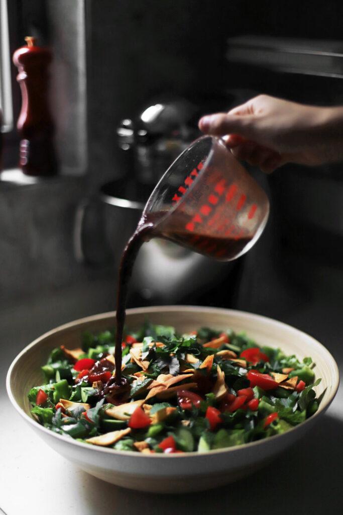 close-up shot of the coffee cardamom dressing being drizzled over the fattoush salad
