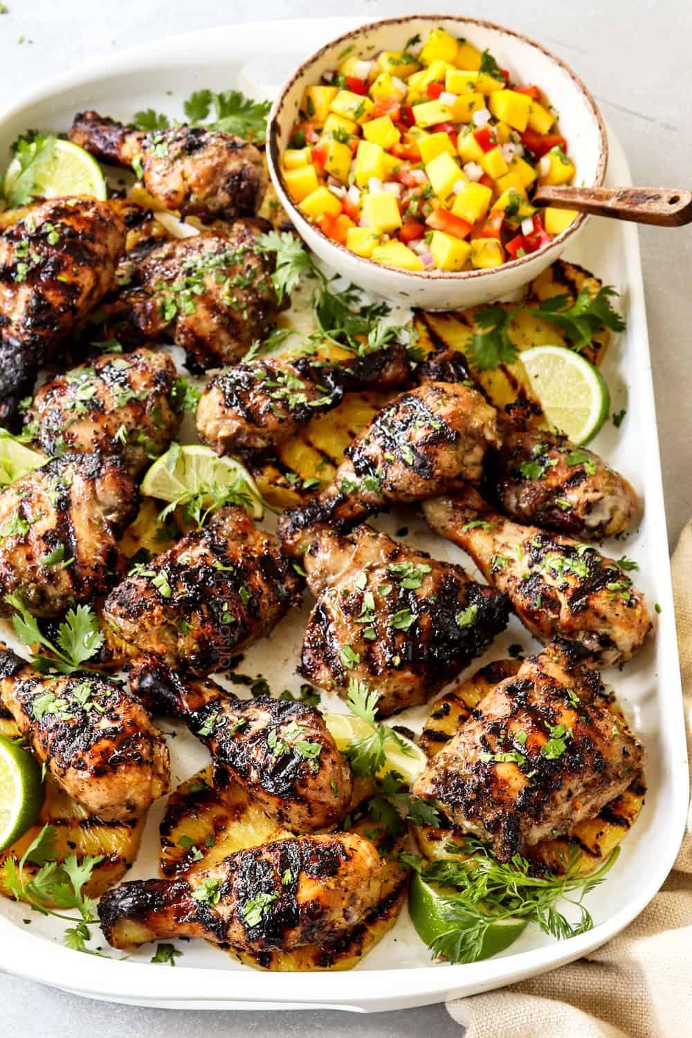 A platter of jerk chicken with jalapeño peppers, garnished with cilantro